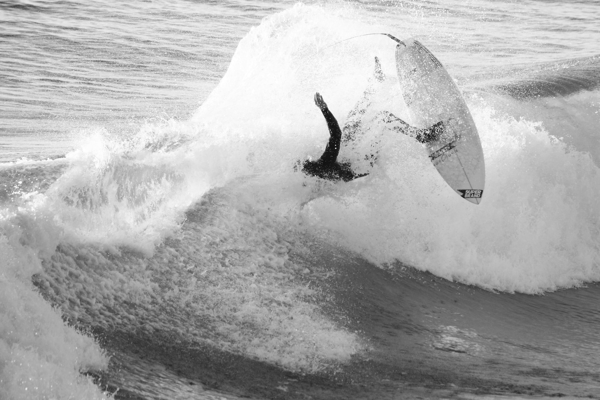 Black & white photo of a surfer falling off their board